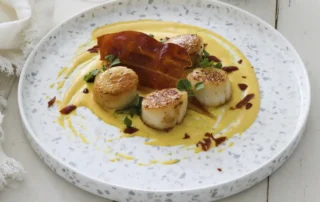 the kitchen doesnt bite scallops with aji amarillo sauce and consorcioserrano ham
